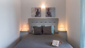 Ein Schlafzimmer mit einem großen Bett, zwei Wandlampen und zwei Kunstwerken über dem Bett.
