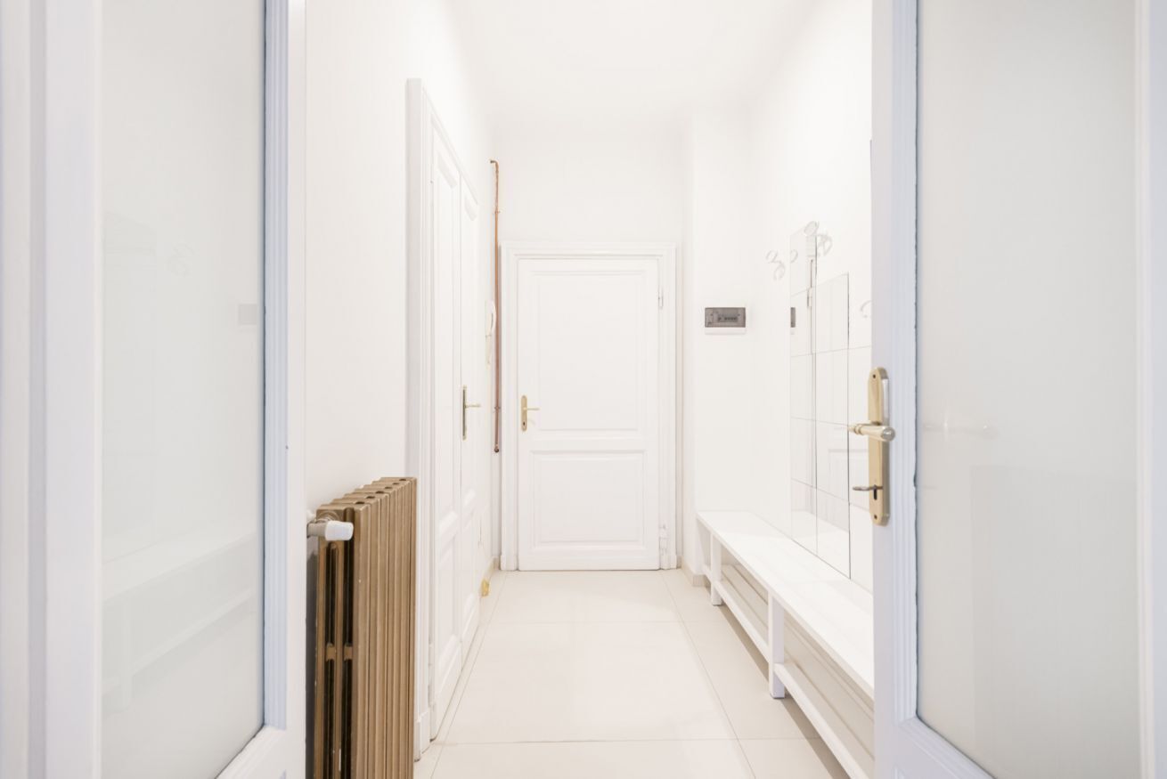 En smal hall med vita väggar och en vit dörr längst in.