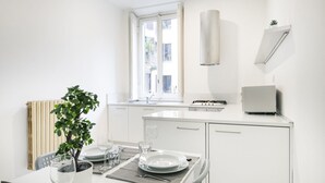 A modern kitchen with white cabinetry, a window, a built-in stove, and a small potted plant. - Easylife - Classy apartment in Buenos Aires (Milano)