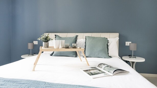 A neatly made bed with a tray of breakfast items, a book, and a magazine on the bed. - Easylife - Classy apartment in Buenos Aires (Milano)