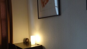 A hotel room with a bed, a desk with a lamp, a framed picture on the wall, and a window with curtains. - Studio in Grenoble city center (Grenoble)