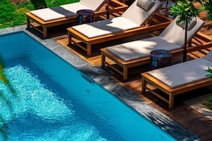 Una piscina al aire libre, sillones reclinables de piscina