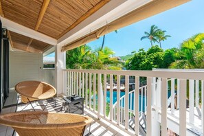 A balcony with wicker chairs, a pool, and lush greenery in the background. - Doudou Hotel by Dina Mogarbine (Saint-Paul)