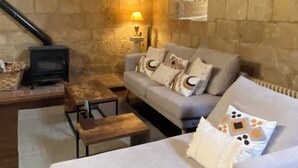 Una habitación acogedora con paredes de piedra, un sofá, una mesita y una chimenea.