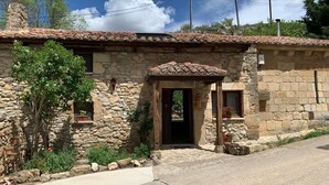 Un edificio de piedra con techo de tejas, una puerta de madera y un pequeño porche.