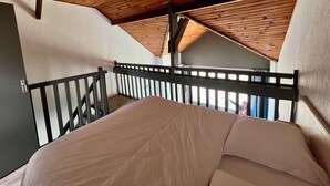 Un dormitorio con techo inclinado, una cama y vista al exterior.