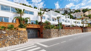 Un edificio moderno con una entrada de pared de piedra, ventanas amplias y cielo despejado.