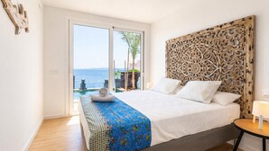 Un dormitorio con cama, vista al mar y un cabecero decorativo.
