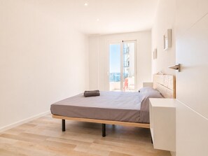 Ein Schlafzimmer mit Bett, Nachttisch, Blick durch eine Tür und einem Balkon.