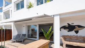 A modern building with a pool, a covered patio, and a dining area with a unique wall decoration.