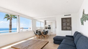 A modern living room with a wooden coffee table, a grey sofa, and a dining area with chairs. - Modern house with air conditioning and private pool in Roses (Roses)