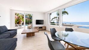 A modern living room with a glass table, grey sofas, and a TV. - Modern house with air conditioning and private pool in Roses (Roses)