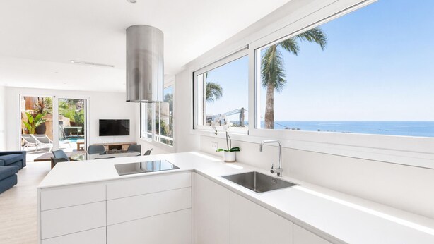 A modern kitchen with a large window, a built-in stove, and a view of the ocean. - Modern house with air conditioning and private pool in Roses (Roses)