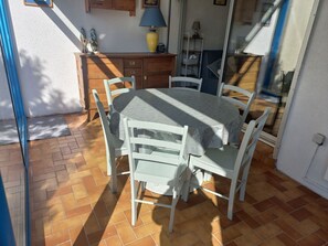 Enjoy meals in this dining area with a round table and six chairs, surrounded by a sliding glass door leading to an outdoor space.