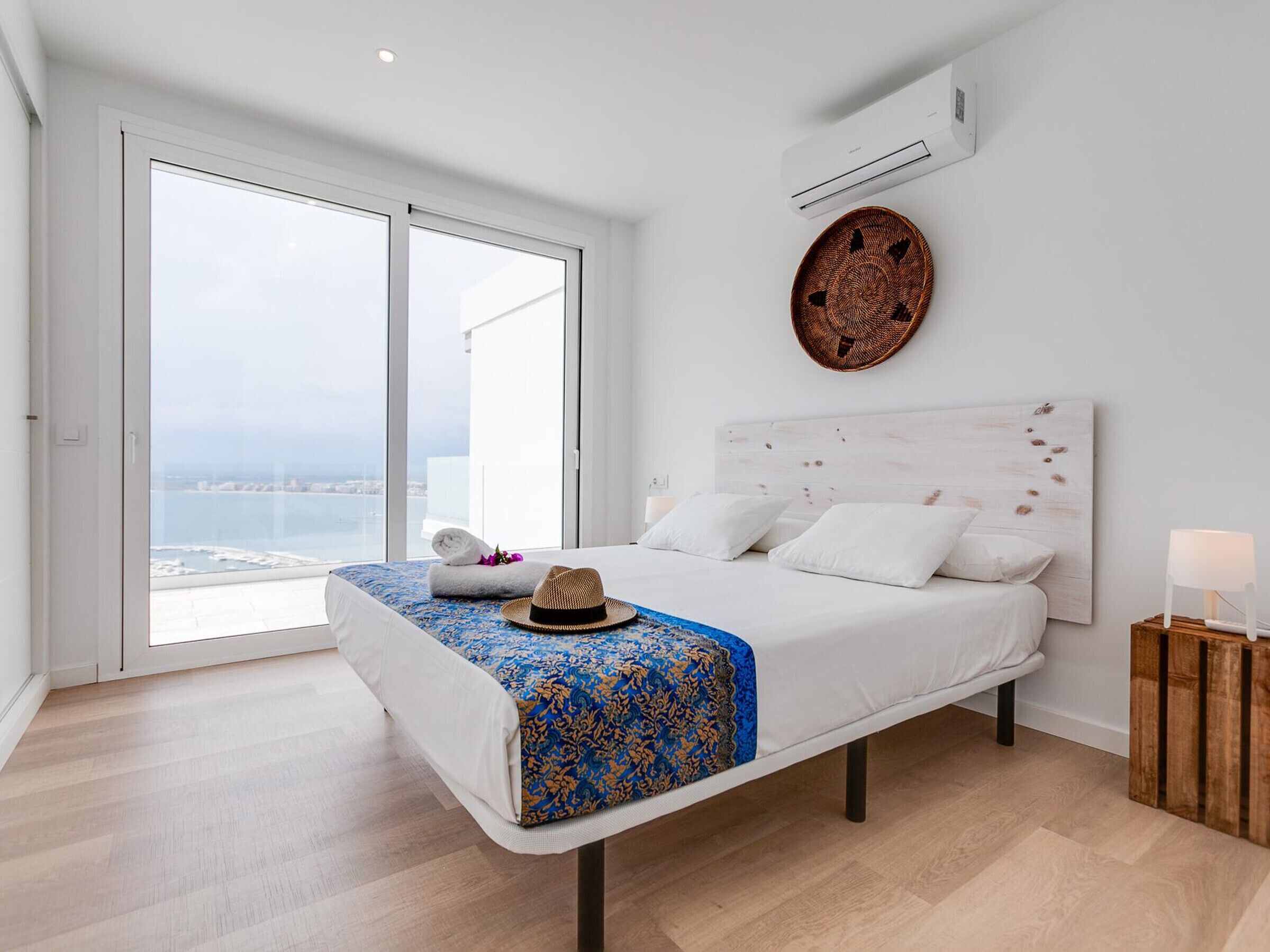 Un dormitorio con una cama grande, vistas al mar y un equipo de aire acondicionado en la pared.