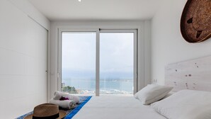 Une chambre d’hôtel avec un grand lit, une vue sur la mer et une tapisserie murale tissée.