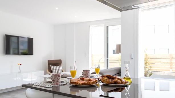A modern kitchen with a central island, a flat-screen TV, and a view of the outdoor balcony. - Luxury apartment in Roses with jacuzzi, close to beach (Roses)