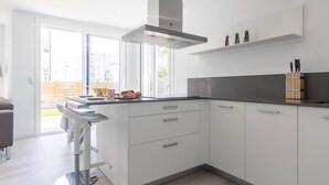A modern kitchen with white cabinets, a stainless steel range hood, and a bar stool. - Luxury apartment in Roses with jacuzzi, close to beach (Roses)