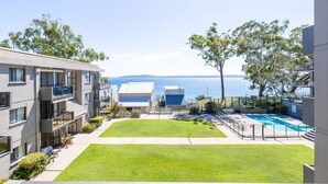 Um complexo de apartamentos moderno com piscina, gramados verdes e vista para o mar.