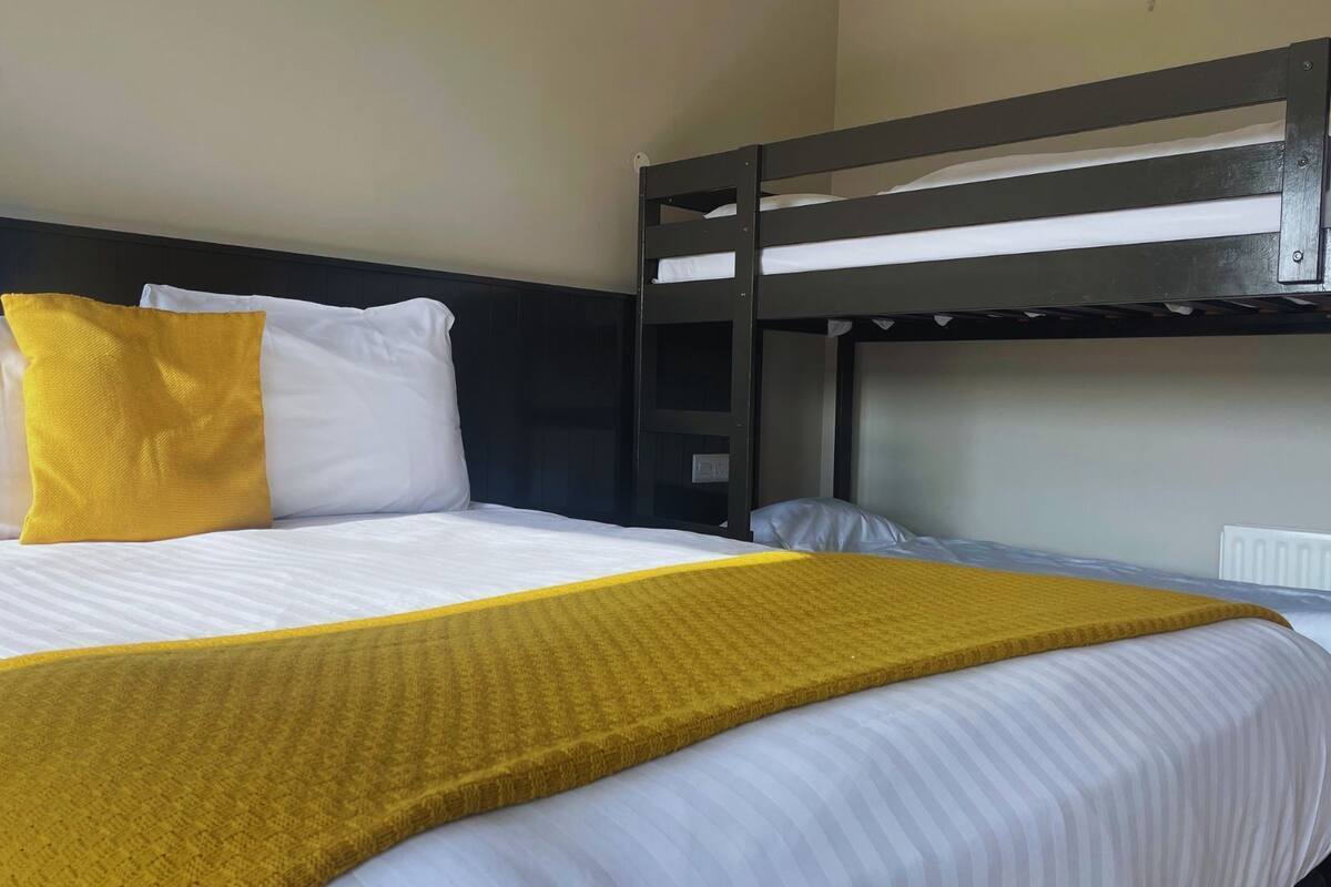 Ein Stockbett mit weißer Bettwäsche und einer gelben Decke.