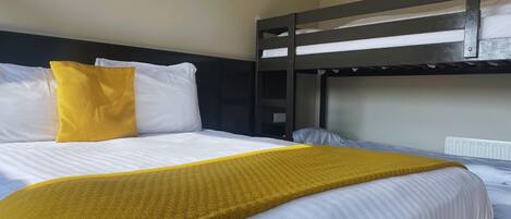 A bunk bed with white bedding and a yellow throw blanket.