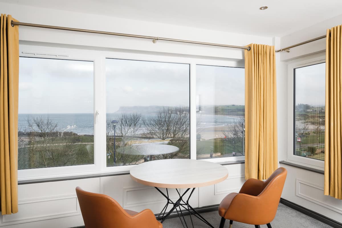 Ein Zimmer mit einem großen Fenster, einem runden Tisch und zwei Stühlen.