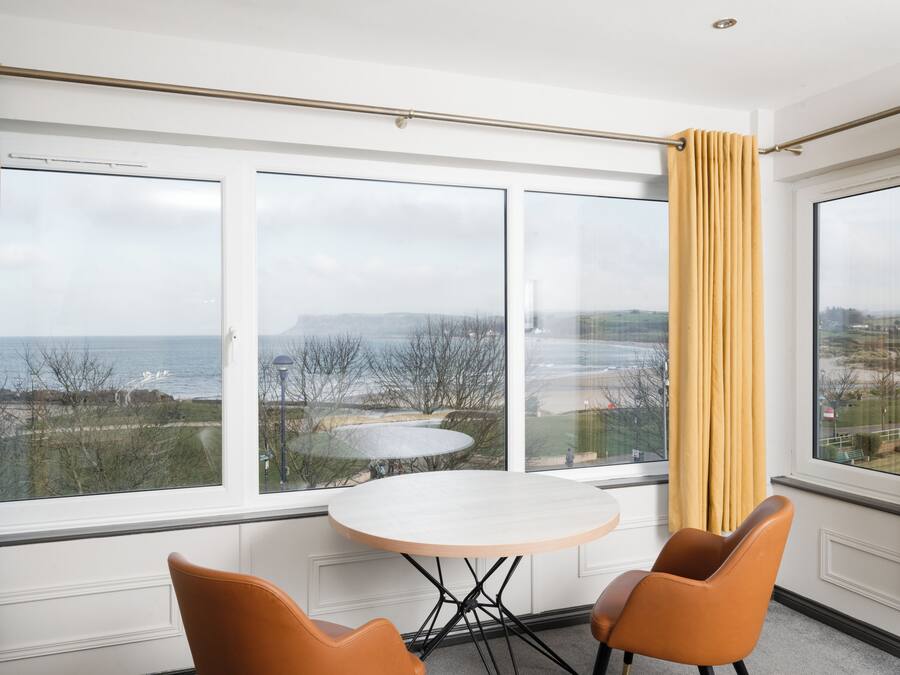 A room with a large window, a round table, and two chairs.