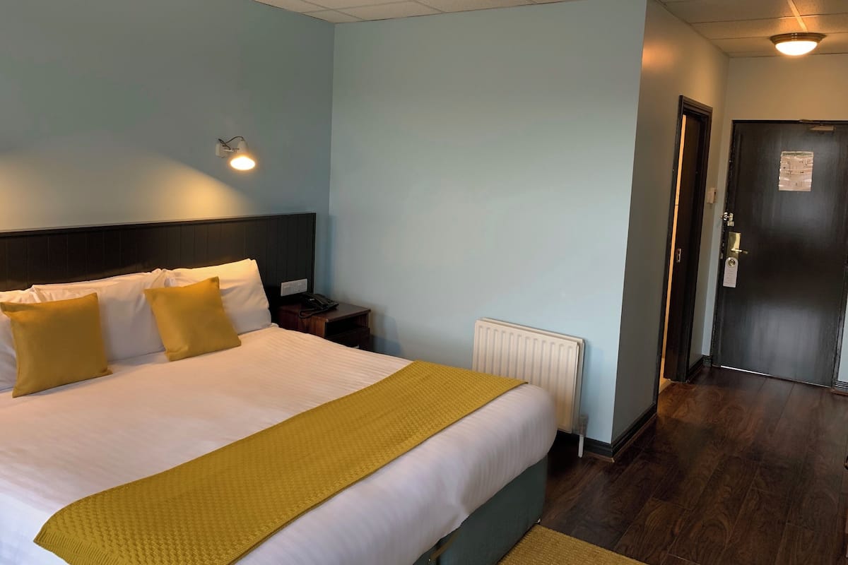 Ein Hotelzimmer mit Bett, Nachttischen, einem Heizkörper und einer Tür.