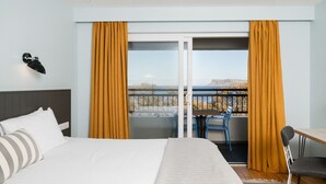 A hotel room with a bed, a desk, a chair, and a balcony with curtains. - Marine Hotel Ballycastle (Ballycastle)