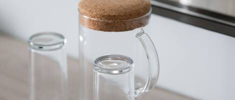 A clear glass mug with a cork stopper and a clear glass container with a cork lid.