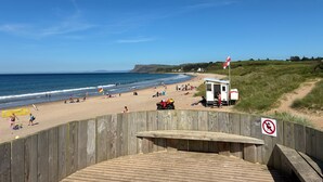 A beach with a wooden boardwalk, a lifeguard station, and a no smoking sign. - Marine Hotel Ballycastle (Ballycastle)