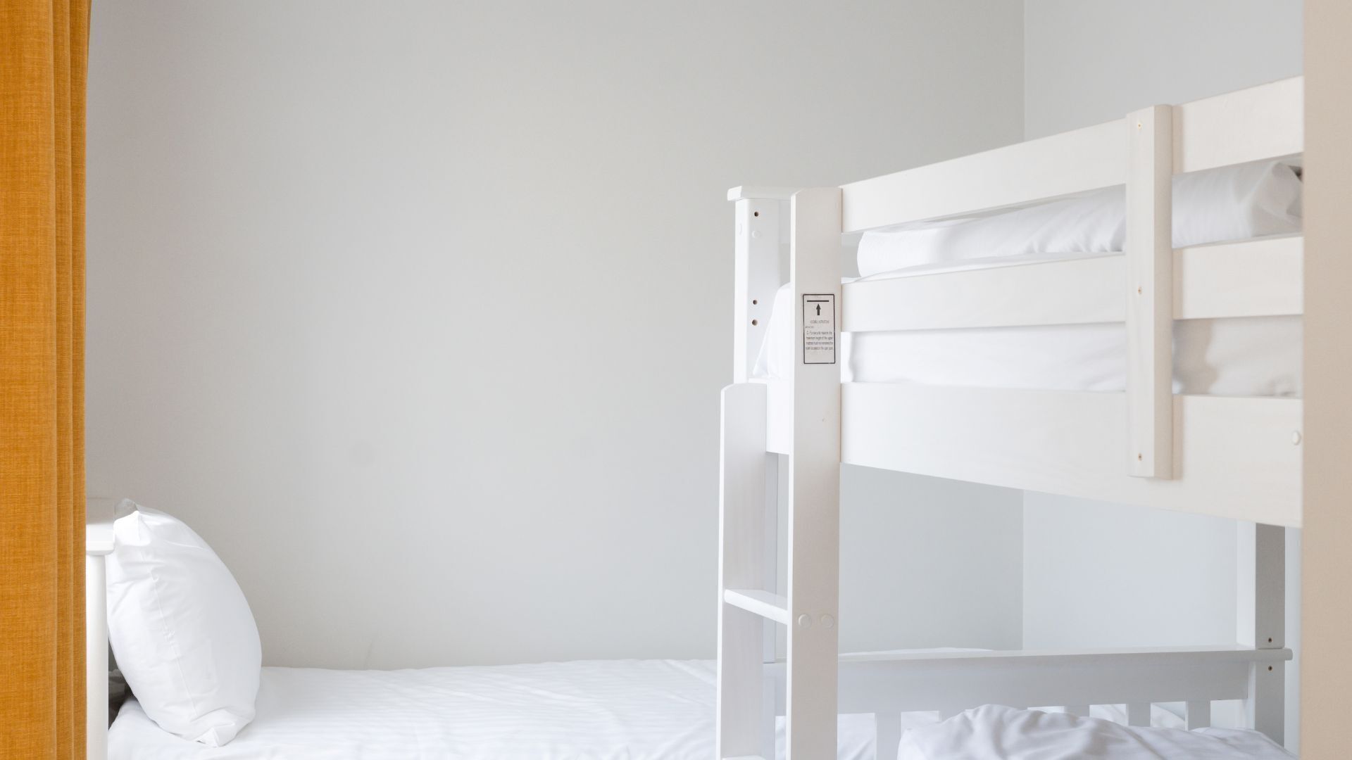 A bunk bed with a control panel, a white mattress, and a white pillow.