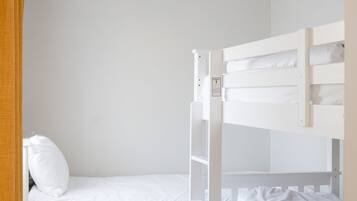 A bunk bed with a control panel, a white mattress, and a white pillow.