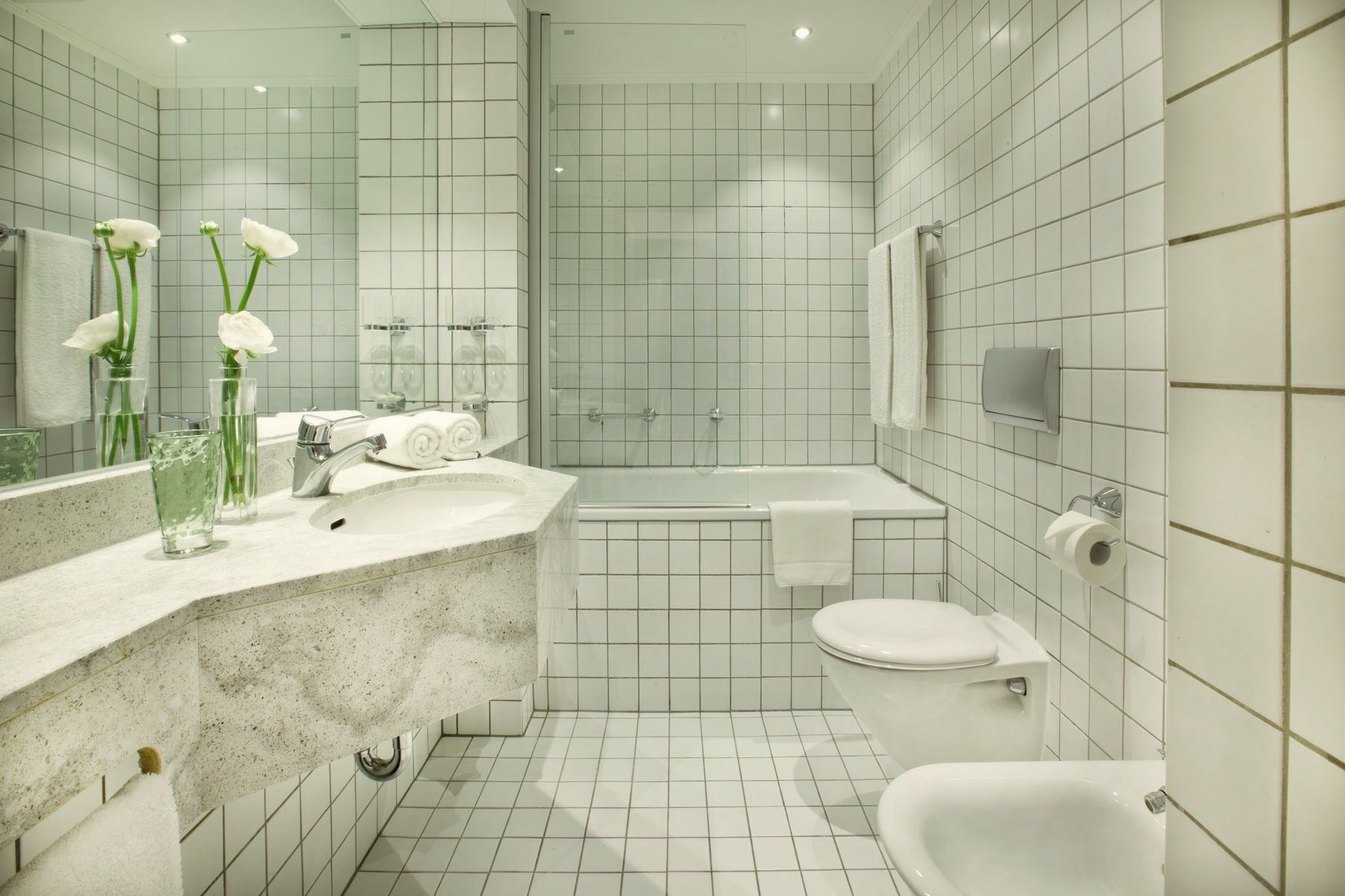 A modern bathroom with a large mirror, a sink, a bathtub, and a toilet.