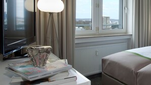 Une chambre d’hôtel avec deux lits, un bureau avec une lampe, une télévision et une fenêtre avec des rideaux.