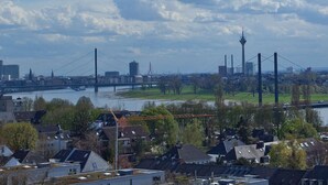 Une rivière traversée par un pont, une vue sur les gratte-ciel d’une ville et des immeubles d’habitation.