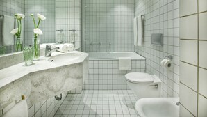 Une salle de bain moderne avec un grand miroir, un lavabo, une baignoire et des toilettes.