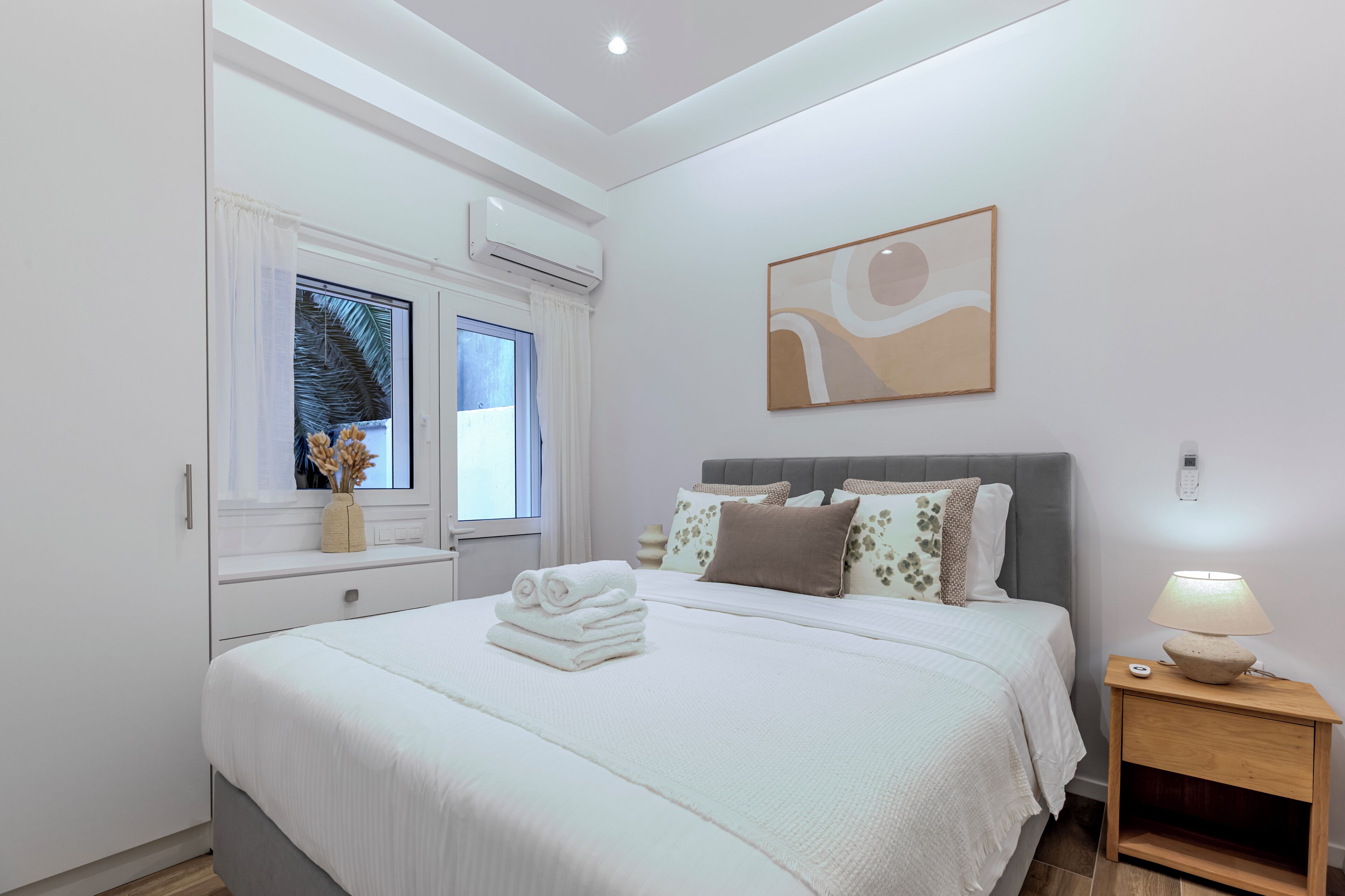 A bedroom with a bed, bedside table, and a window with curtains.