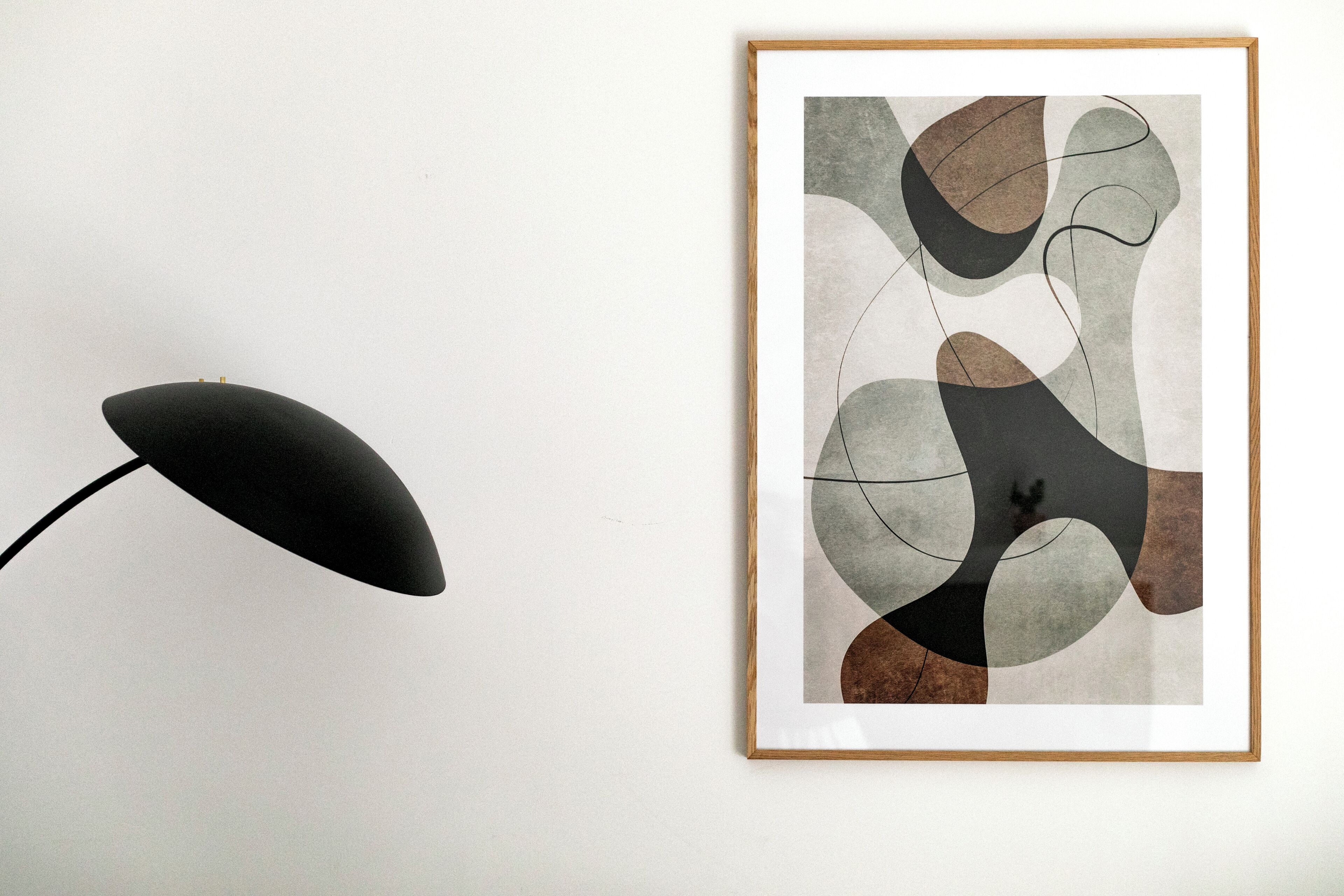 Pintura abstrata emoldurada numa parede, ao lado de um candeeiro de chão preto.