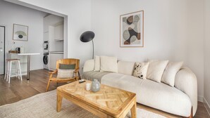Una sala de estar moderna con un sofá, una mesa de centro de madera, una silla y una lámpara de pie.