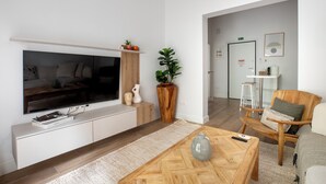 Una sala de estar moderna con un televisor de pantalla plana, una mesa de centro de madera y una planta grande en maceta.