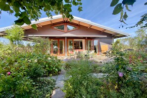 A modern house with a large glass door, surrounded by lush greenery and a clear sky. - Hestar Husid, a designer home with a garden near Amsterdam (Weesp)