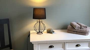 A white desk with a lamp, a small turtle figurine, and folded towels on top.