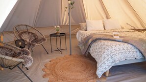 Une tente équipée d’un lit, de deux chaises, d’une petite table et d’un tapis décoratif.