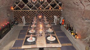 A long dining table set with candles, wine glasses, and plates with napkin cones, surrounded by wine bottles and a wine rack in the background. - Vacation apartment/house with 2 bedrooms in the historic Vierkanthof (Mechernich)