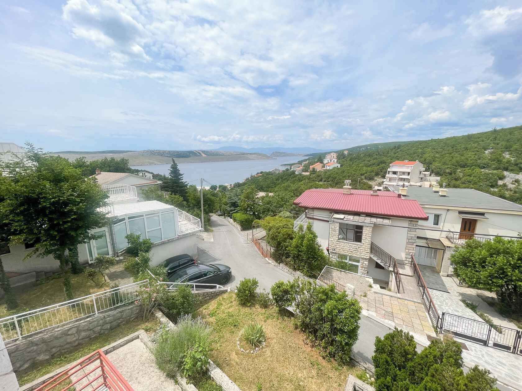 A residential area with houses, a road, and a body of water in the background.