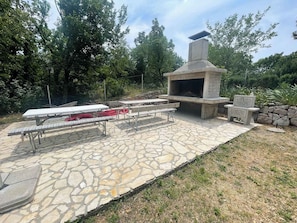 Guests can enjoy a peaceful atmosphere in this outdoor patio area with a fireplace, picnic tables, and benches.
