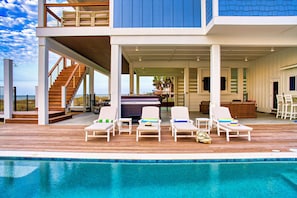 Uma casa moderna com piscina, área de estar ao ar livre e escadaria para uma varanda.