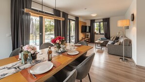 A modern living room with a dining area, a sofa, and a TV mounted on the wall. - 6 persons Chalet Bergherzerl in the Chiemgau. Summer pool, whirlpool & sauna (Inzell)