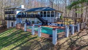 A two-story house with a swimming pool, a covered patio, and a fenced deck.